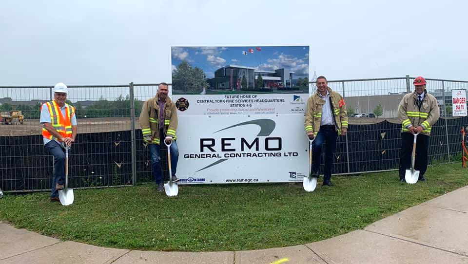 Four men in hard hats and hi-vis vests holding shovels at a groundbreaking ceremony for a new building, with a sign that reads "REMO General Contracting Ltd.