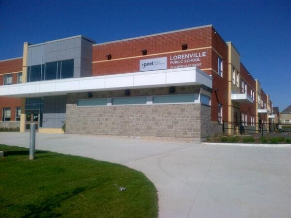 Exterior view of Lorenville Public School on a sunny day, featuring its modern brick building and paved courtyard.