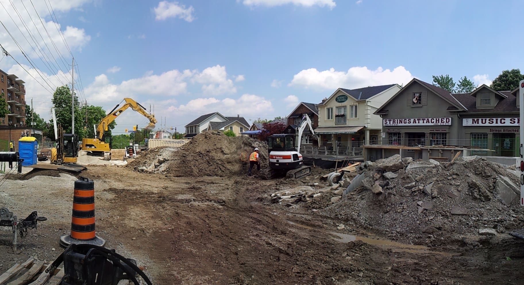 Construction site with workers, heavy machinery, and partially demolished buildings under a clear sky.